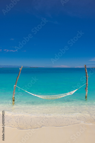 Peaceful hammock swing white sand beach turquoise ocean lagoon, sunny blue sky paradise island coast vertical. Summer vacation travel relax tropical holiday getaway background wallpaper landscape