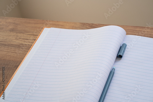 Open lined notebook with pen on a wooden desk