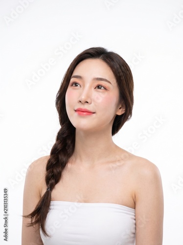 young woman with long dark braided hairstyle, natural makeup, wearing a white strapless tube top, looking upward, with a hopeful expression, isolated on a white seamless studio background