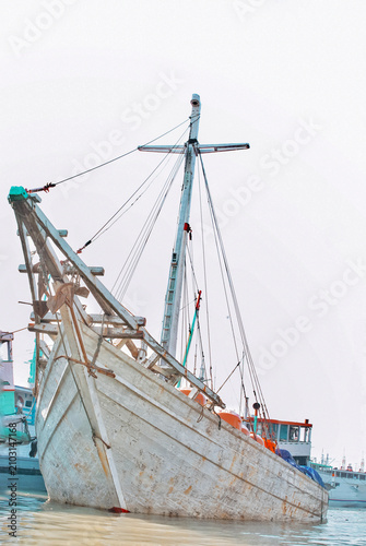 Traditional Indonesian wooden cargo vessel at Sunda Kelapa Port, Jakarta, Indonesia. Historic harbor with active coastal shipping, maritime heritage, and working port operations.