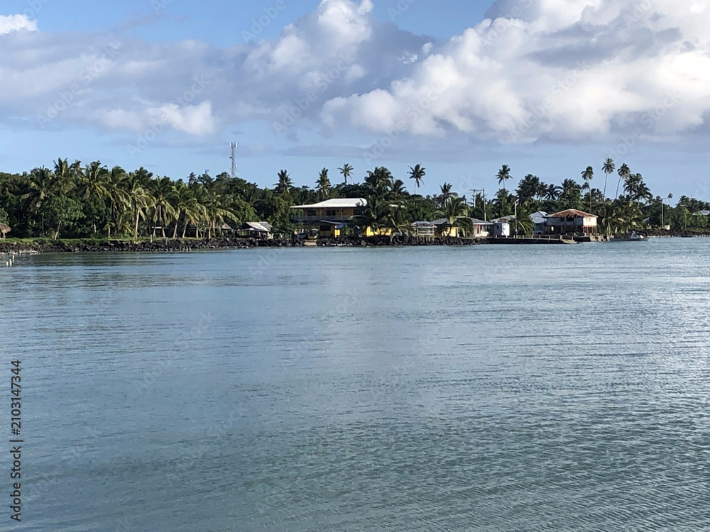 Fototapeta premium Samoan coastal village beneath dramatic tropical storm clouds