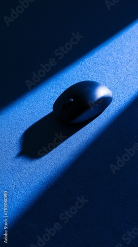 A sleek black computer mouse in blue light.