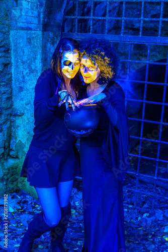 Fotografie Halloween witches casting spell using magic cauldron