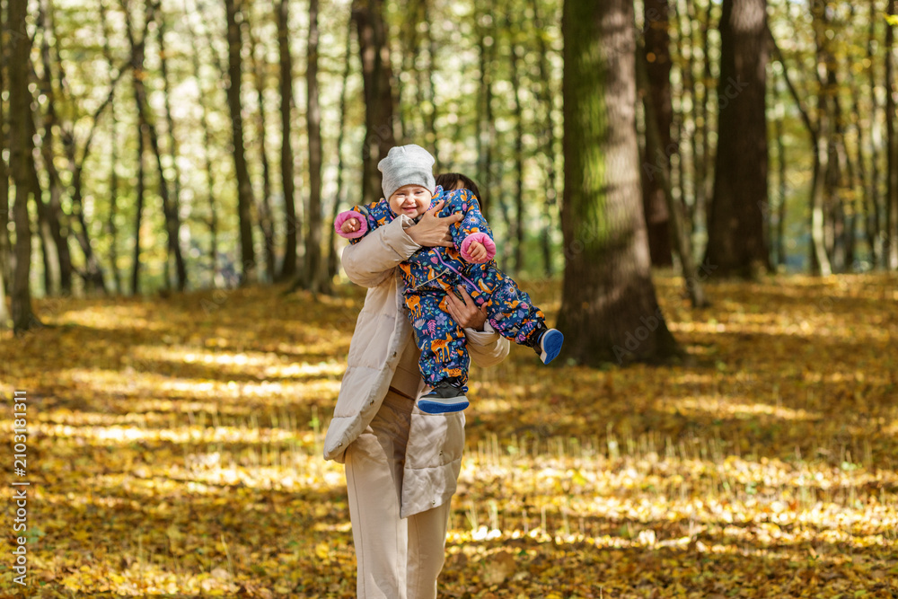 Fototapeta premium Smiling Baby in Mother's Arms During Autumn Forest Walk