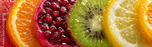 Colorful slices of fresh fruit arranged in a line showing different textures and juices in bright lighting