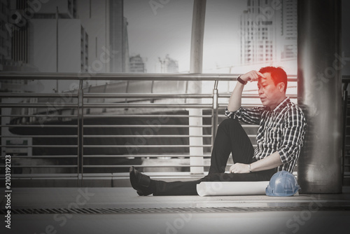 Asian engineer man who sitting on the floor in feeling sad because his business failed and unemployed. Business failed concept.