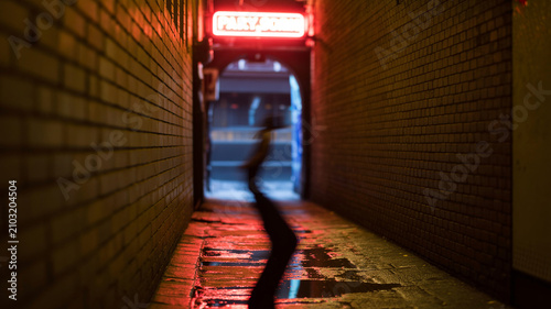 Gothic alleyway with neon signs and shadowy figure