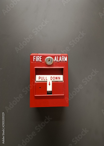Fire alarm pull station on a wall, red emergency device with warning labels, concept of building safety and fire protection.