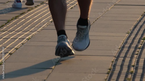 Close-Up of Runner Jogging Along Sidewalk During Sunset