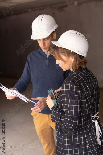 Architects and engineers collaborating on a construction site, discussing building plans and using digital devices for project management and development inspection