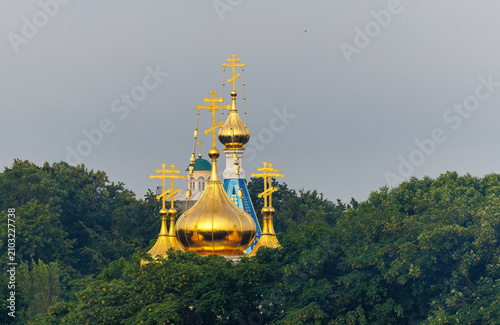 Фотография Golden domes of an Eastern Orthodox church rising above trees in Ventspils, Latv