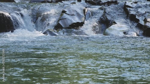 Mountain River with Small Waterfall Flowing Over Smooth River Rocks 