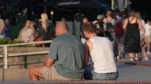 Rear View of People Relaxing in a Busy City Park at Sunset
