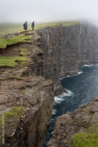Fotografía Hikers wearing raincoats standing on the edge of Trælanípa sea cliffs in the Far