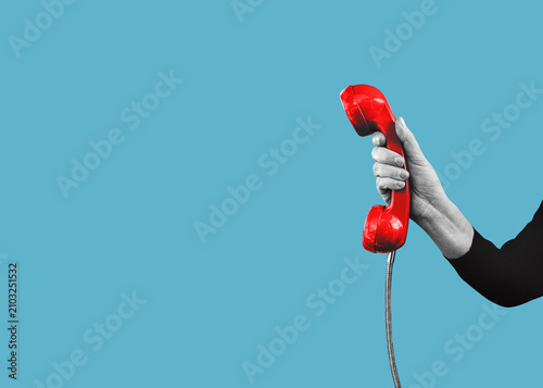 Foto A hand holds a red landline telephone with copy space, isolated on free background