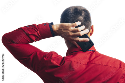 A man in a red shirt, holding a phone, is standing with his back to the camera on a white background.