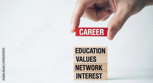 Human hand holding red wooden block with word career on top of other wooden blocks with words education, values, network, interest.