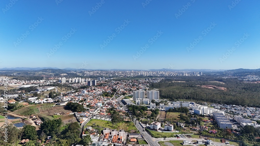 Fototapeta premium Imagem aérea de bairro em expansão com residências em construção, ruas organizadas e infraestrutura urbana em desenvolvimento, representando o crescimento imobiliário.