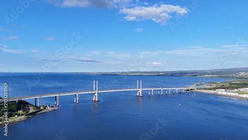 Inverness, Scotland, British coastal city enjoys clear daytime skies, overlooking the sea with a magnificent bridge amid stunning Highland landscapes.