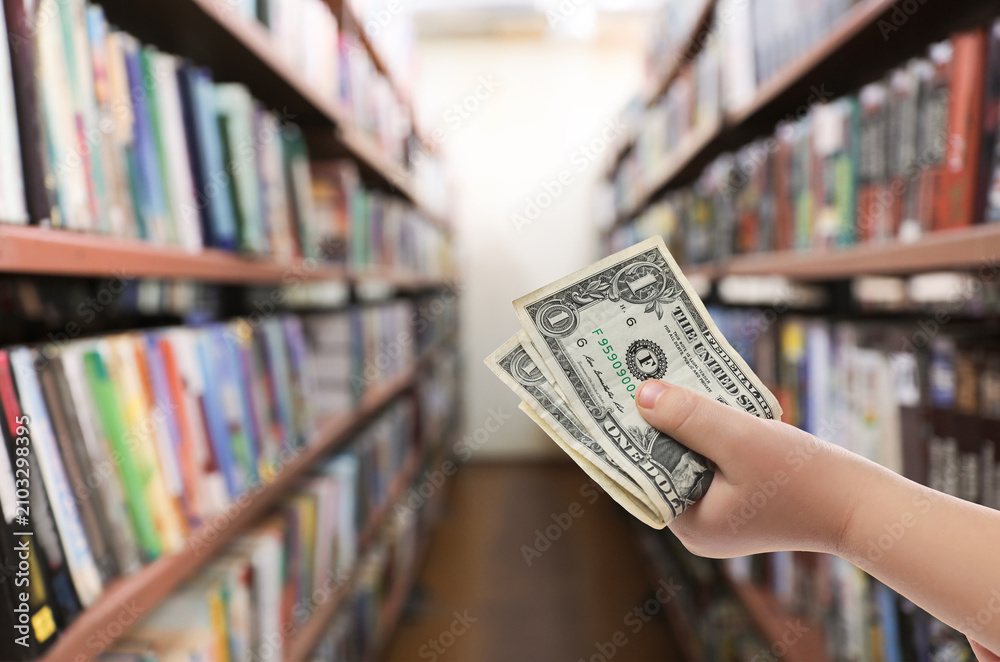 Fototapeta premium Little child with pocket money in bookstore, closeup