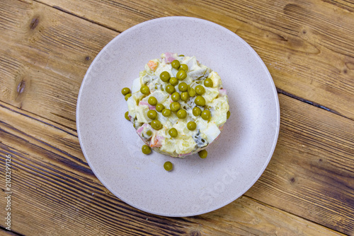 Ceramic plate with new year salad olivier on a wooden table. Top view