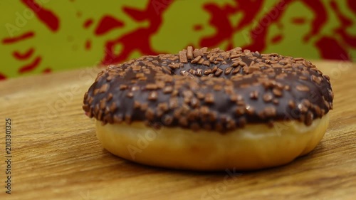 A chocolate glazed donut on wood.
