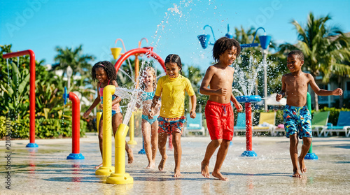 Diverse group of children running and playing in a sunny outdoor splash pad