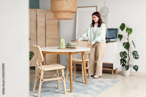 Fotografia Young woman pulling chair at table in dining room