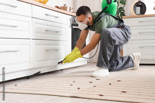 Bild auf Leinwand Male pest control specialist disinfecting floor for cockroaches in kitchen
