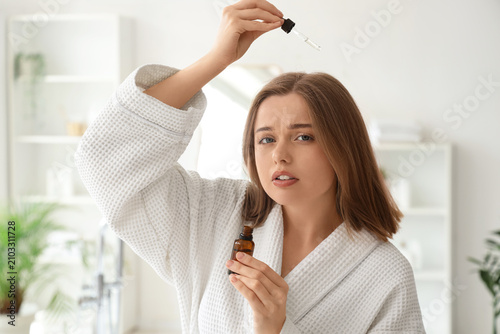 Young woman using serum for...