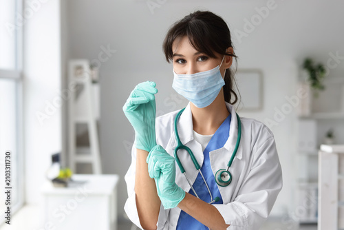 Female medical intern with mask and gloves in clinic