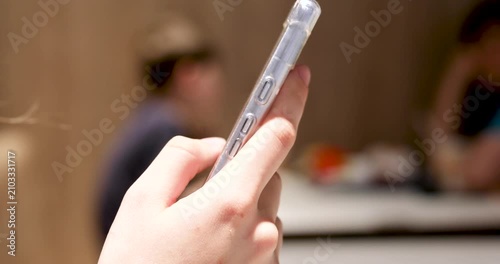 browsing her smartphone and swiping with her thumb while in a restaurant.