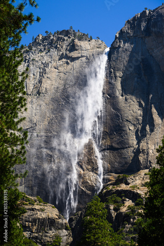 Windblown water cascades over Upper Yosemite Falls in summer creating a mist