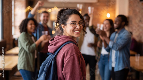 Back to school college party portrait. Happy Gen Z female university student in glasses and maroon hoodie looking over shoulder during freshman orientation social mixer event on campus quad, September