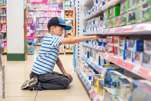 Little boy selecting toy in retail store, childhood shopping experience and consumer choice. Young child browsing toy store shelf