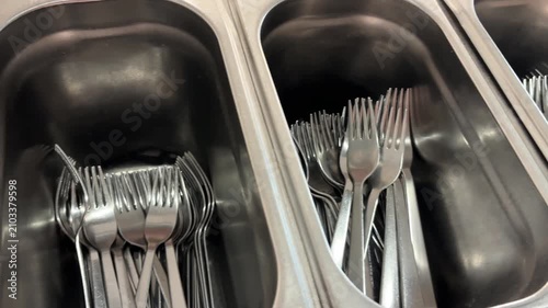 Stainless steel cutlery containers with forks and knives in a restaurant, cafeteria or commercial kitchen self-service area