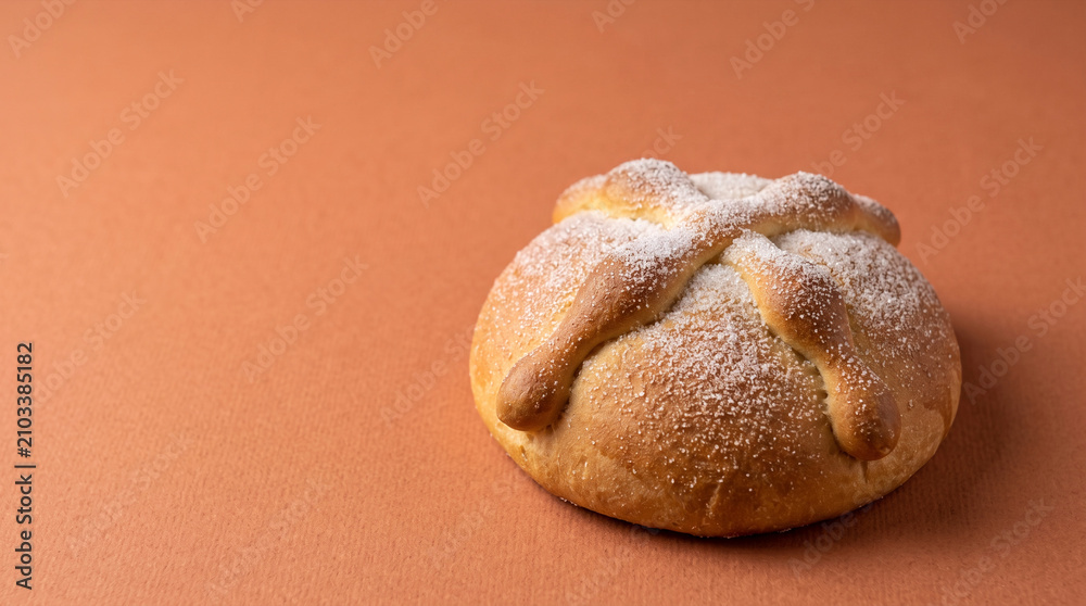 Fototapeta premium Pan de muerto bread sprinkled with sugar on a warm colored background