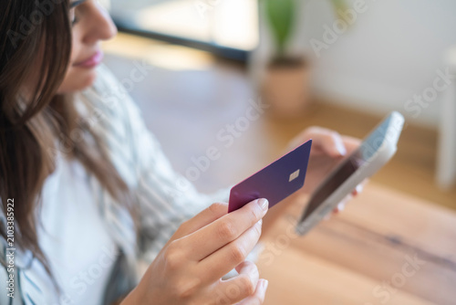 Konstfotografi Young woman holding credit card and smartphone making secure online payment for