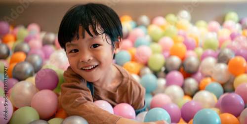 Принти на полотні Happy little boy smiling and playing in a colorful ball pit enjoying childhood