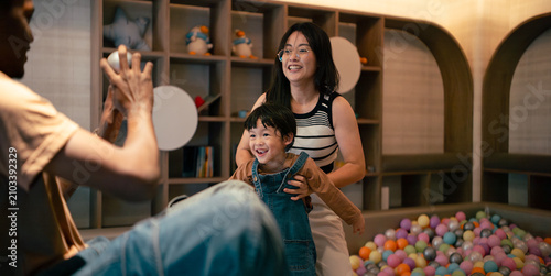 Happy family parents child playing together having fun in indoor modern play area