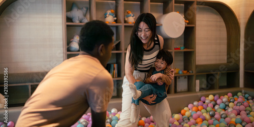 Принти на полотні Multiethnic family enjoying playtime in ball pit, parents laughing with happy ch