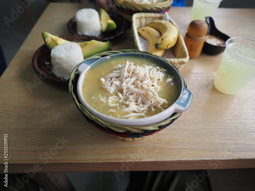 Bowl of soup with shredded chicken served with rice, bananas, and avocado at a local restaurant.