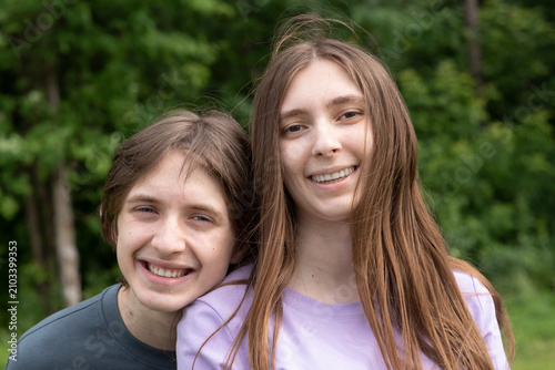  Happy teenage brother and sister smiling together outdoors in park