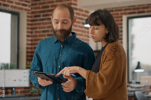 Business people reviewing information on digital tablet in a startup office  working with laptop  charts and paperwork for financial analysis and project planning.