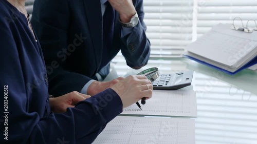 Professional auditors and accountants reviewing financial documents, discussing data, calculating taxes and expenses during an important business audit meeting