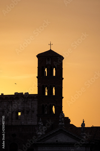 Bell tower silhouetted against a vibrant sunrise sky, highlighting the timeless skyline and historic architecture of Rome