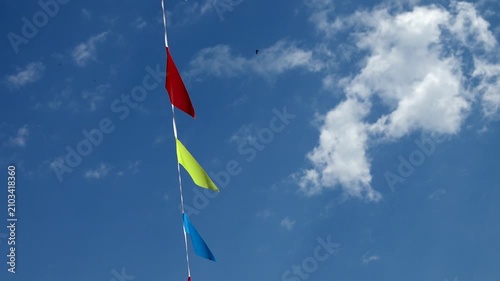 Colorful prayer flags flutter against a bright blue sky  .Tibetan prayer flags in vibrant colors are strung together and blowing in the wind against a clear blue sky with fluffy white clouds