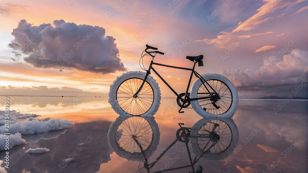 Fototapeta premium Vintage bicycle on a salt flat at sunset. Retro bike parked on reflective water surface.
