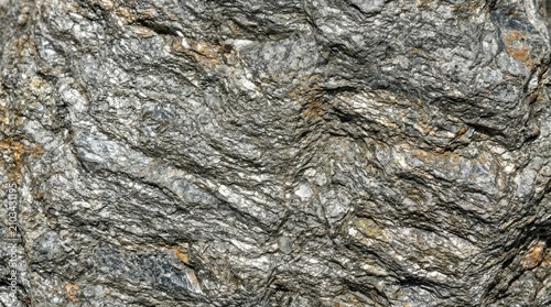 Close up of grey schist metamorphic rock texture with visible foliation and mineral grains for geological background and natural stone surface design