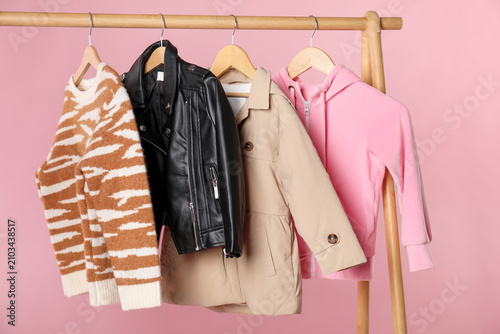 Obraz na plátně Stylish child's clothes on wooden rack against pink background